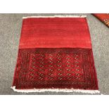 An eastern fringed cushion cover on red ground,