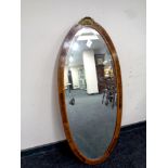 An oval French inlaid framed bevel edged mirror surmounted by an ormolu mount