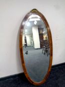 An oval French inlaid framed bevel edged mirror surmounted by an ormolu mount