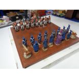 A chess board with figural pieces,