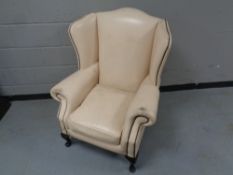 A wingback armchair upholstered in a cream button leather
