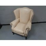A wingback armchair upholstered in a cream button leather