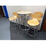 A circular poser bar table on metal legs together with a set of four bar chairs on metal legs