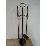 An antique brass two piece fire companion set on stand