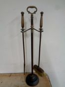 An antique brass two piece fire companion set on stand