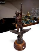 An antique spelter figure of a man riding an eagle on a circular oak base,