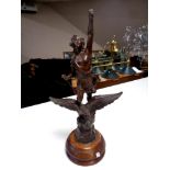 An antique spelter figure of a man riding an eagle on a circular oak base,