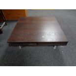 An Ikea square low coffee table on metal legs,