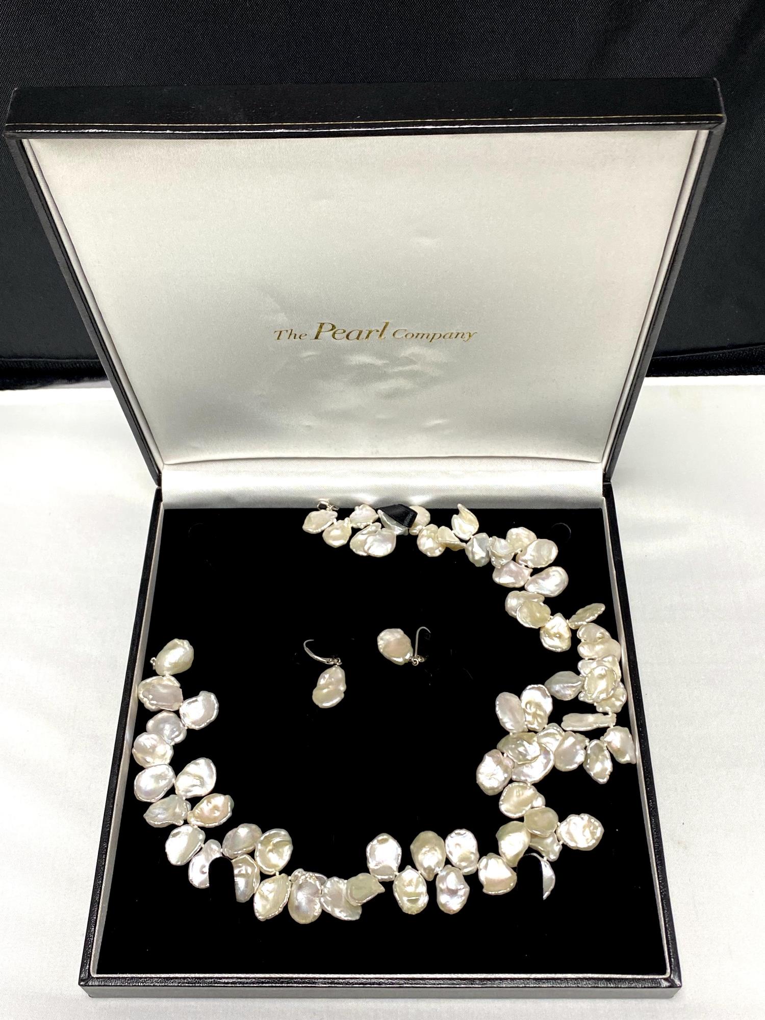 A silver mounted pearl necklace and matching earring set