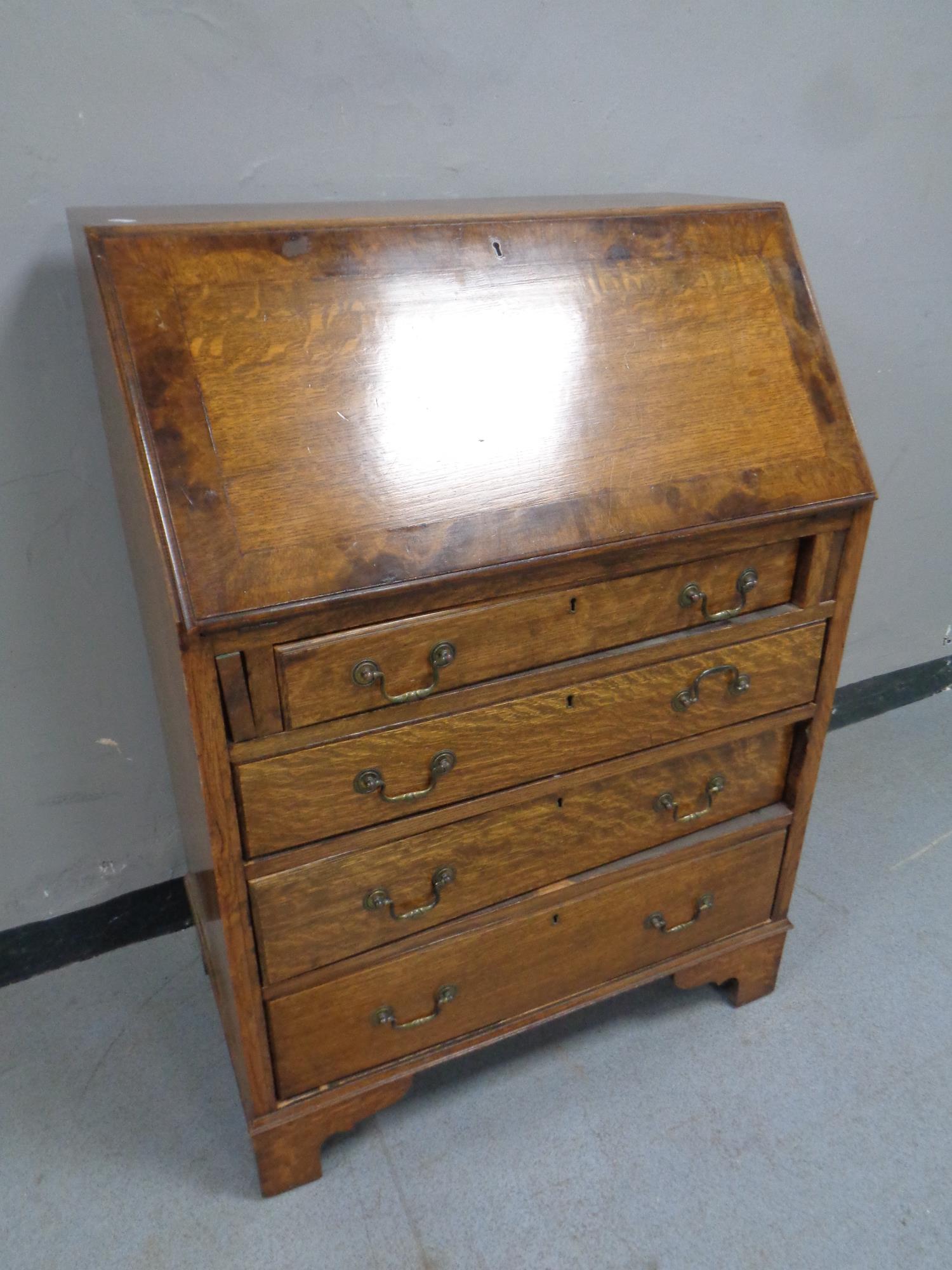 A 19th century oak writing bureau fitted four drawers beneath