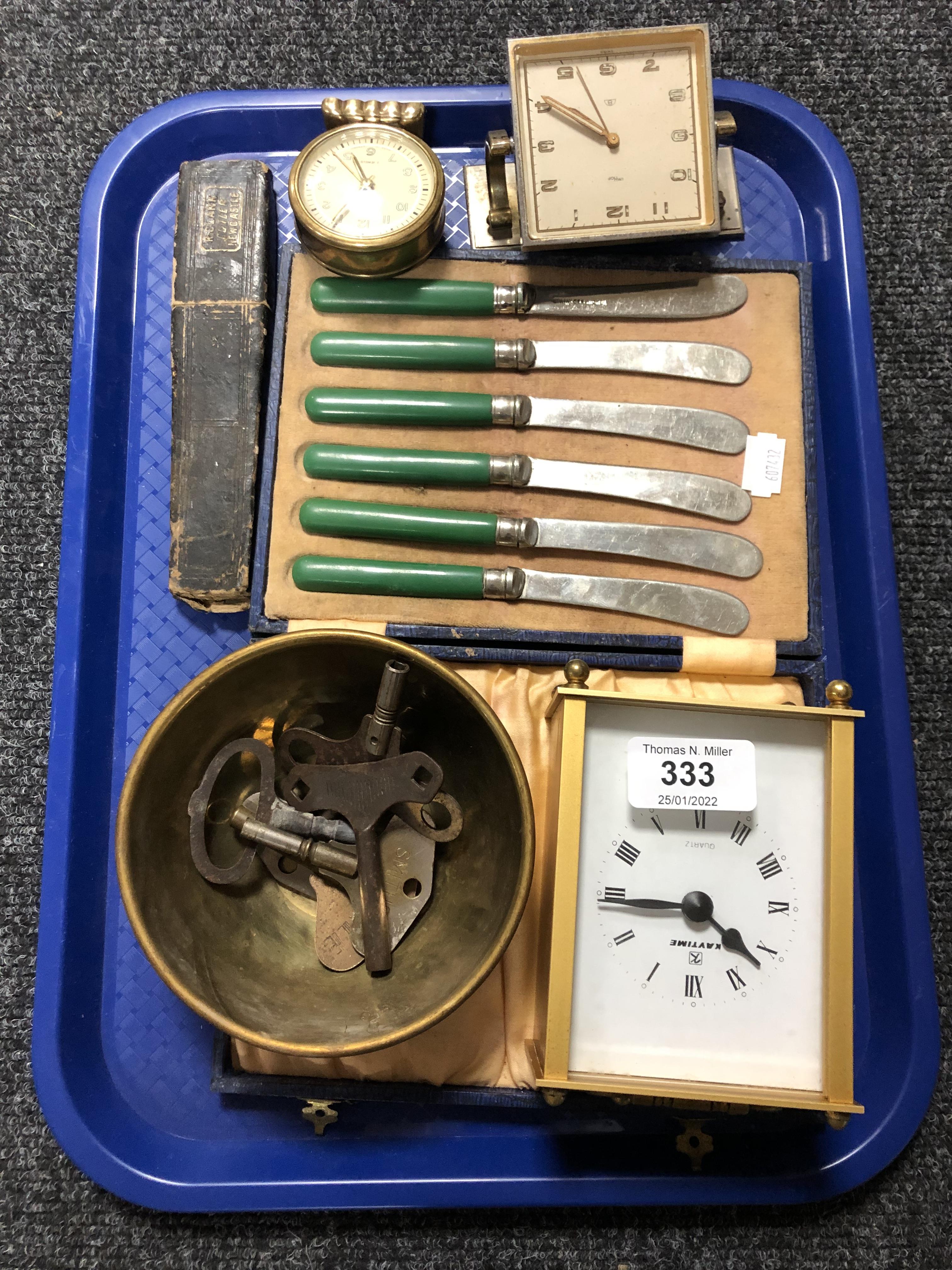 A tray containing cased butter knives, clock keys, desk clocks, mantel clock,