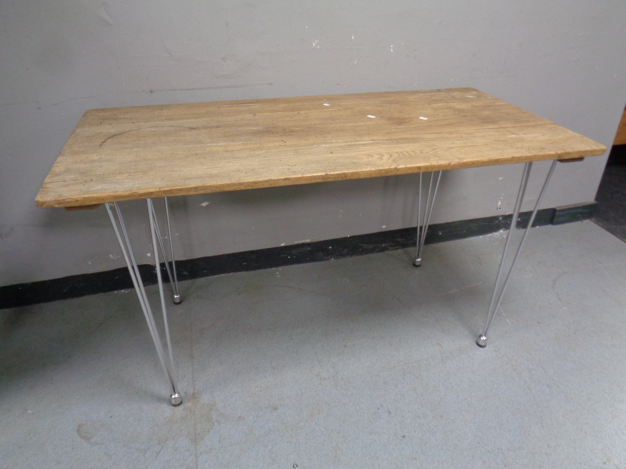 A 20th century wooden plank top table on metal hairpin legs,