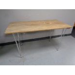 A 20th century wooden plank top table on metal hairpin legs,