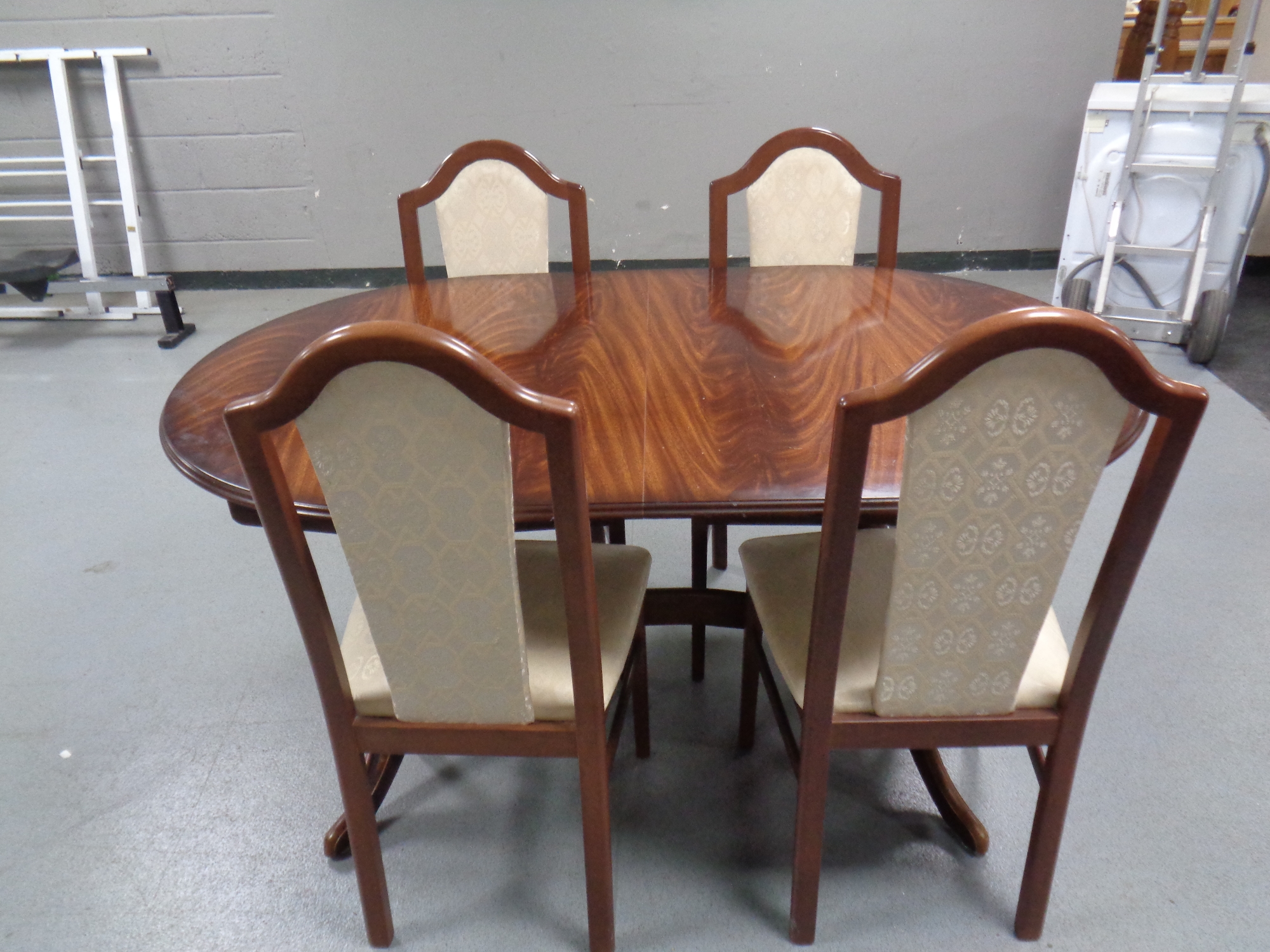 An oval extending dining table together with a set of four chairs in a mahogany finish