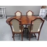 An oval extending dining table together with a set of four chairs in a mahogany finish