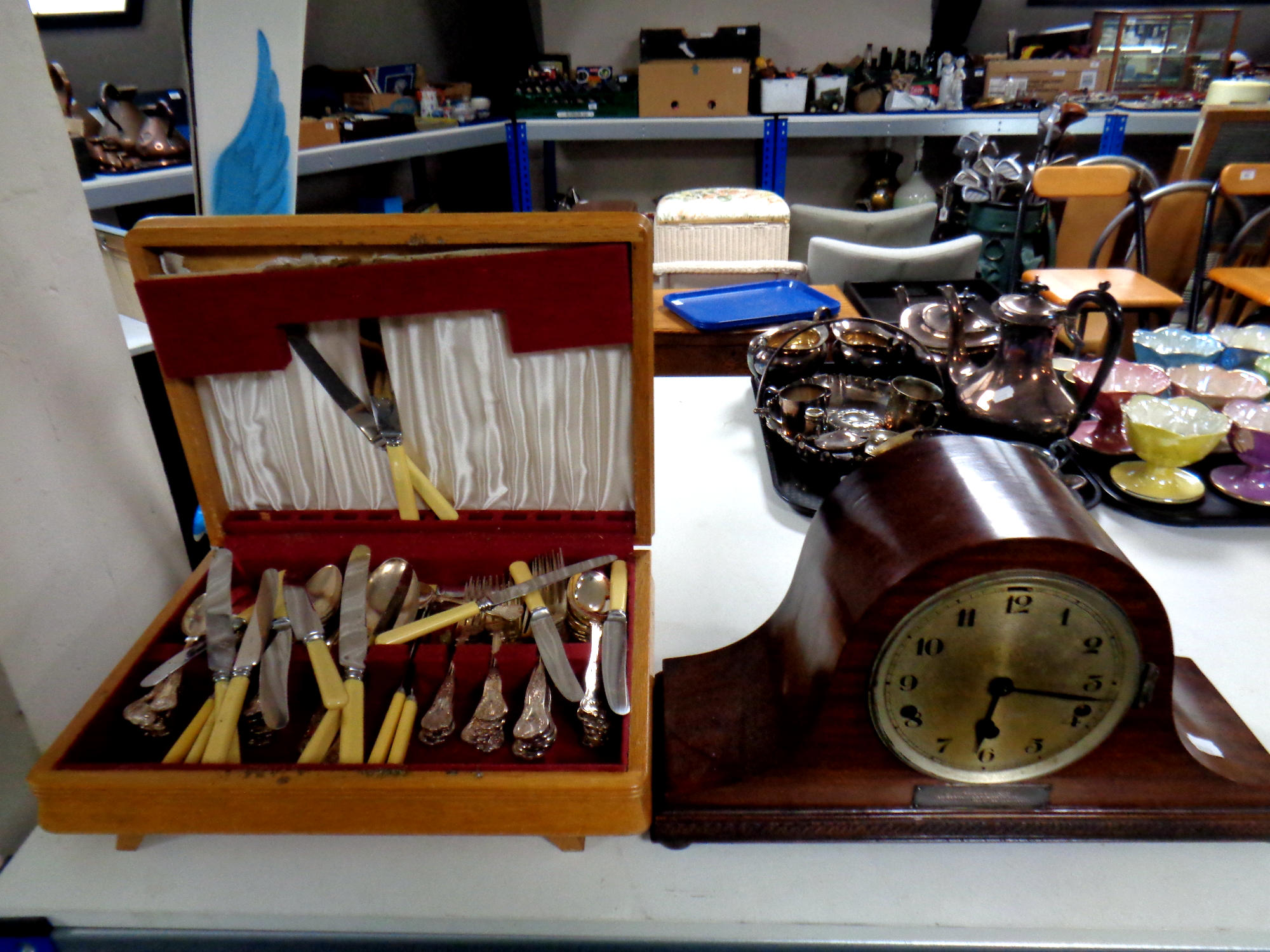 A canteen containing plated cutlery together with a mahogany cased mantel clock with silvered dial