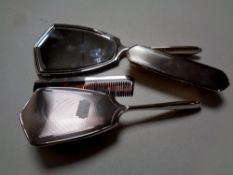 A four piece silver backed dressing table hand mirror and brush set,