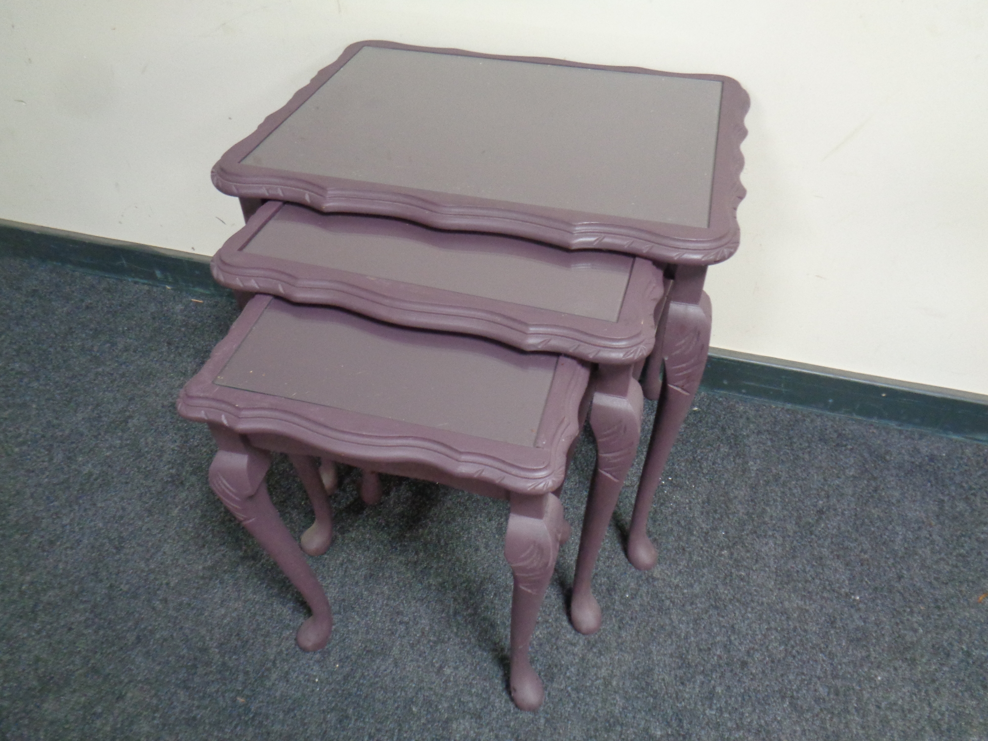 A nest of three painted glass topped tables