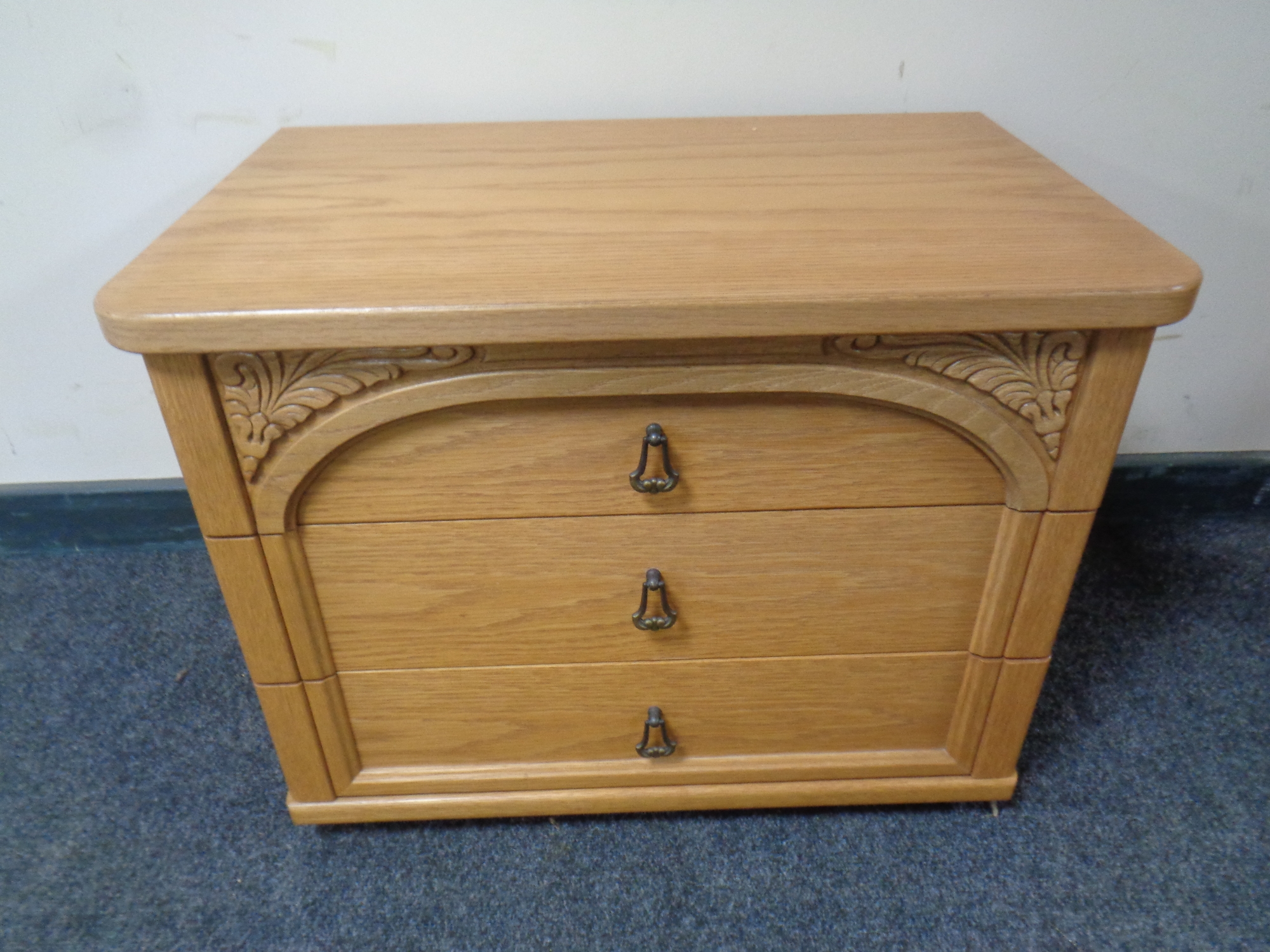 A three drawer bedside chest in oak finish