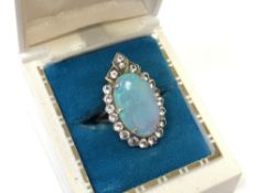 A vintage opal ring, set in Art Deco style with a border of white moissanite in yellow metal,
