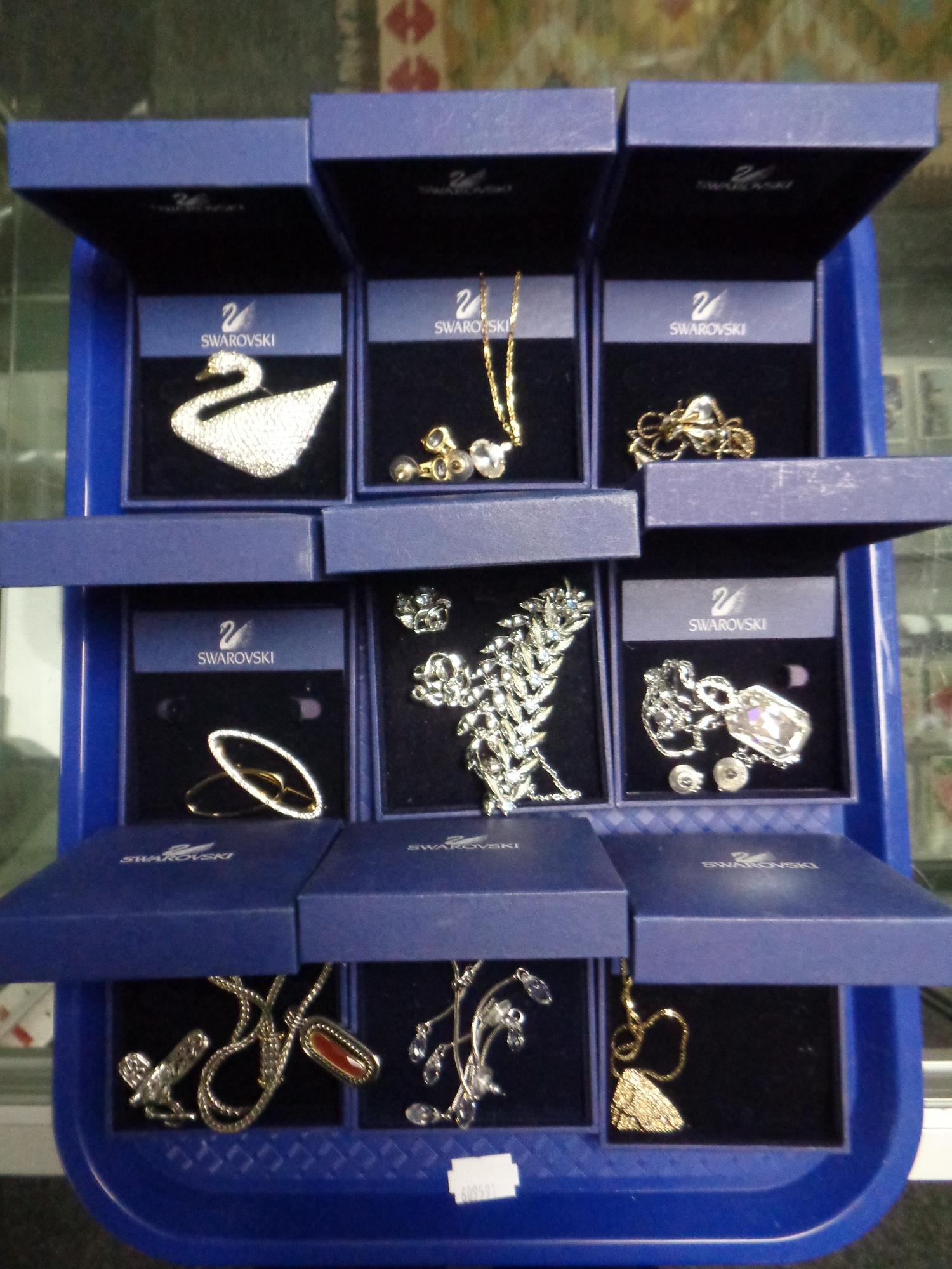 A tray containing nine pieces of Swarovski jewellery to include brooches, pendants, earrings etc,