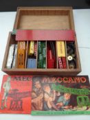 A wooden storage box containing vintage Meccano and instruction booklets