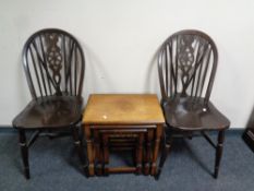 A pair of wheel back chairs together with a nest of three oak tables