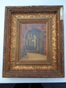 An early 20th century oil on board depicting an archway with dwelling beyond in a gilt composite
