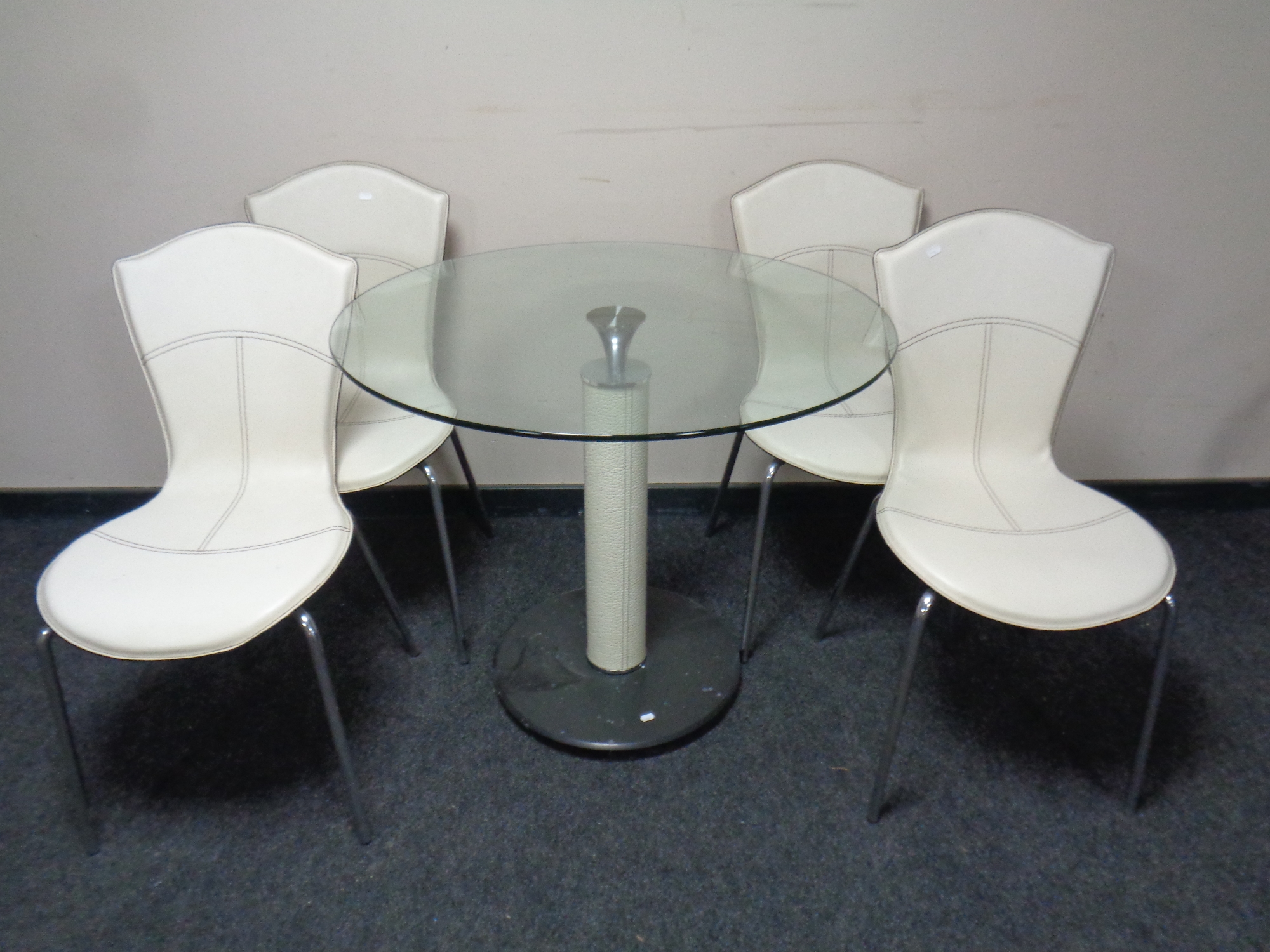A contemporary circular glass topped pedestal dining table together with a set of four cream faux