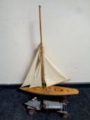 A wooden model of a yacht on stand together with a contemporary tin plate vintage racing car