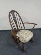 An Ercol solid elm and beech Windsor swan back rocking chair in an antique finish