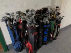 Twelve golf bags containing a large quantity of children's and adult's drivers,