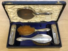 A five-piece silver dressing table set (mirror and four brushes), in a fitted satin-lined case.