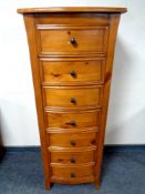 A contemporary pine bow fronted narrow seven drawer chest