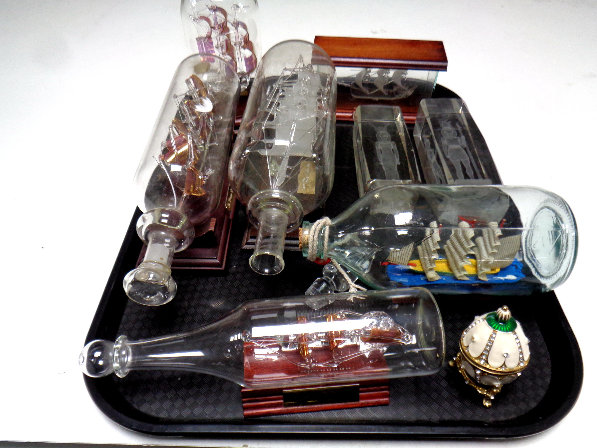 A tray containing six ships in bottles and display cases to include H.M.