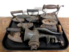 A tray containing seven antique cast iron flat irons together with a vintage mincer