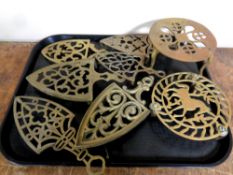 A tray containing seven antique brass trivets