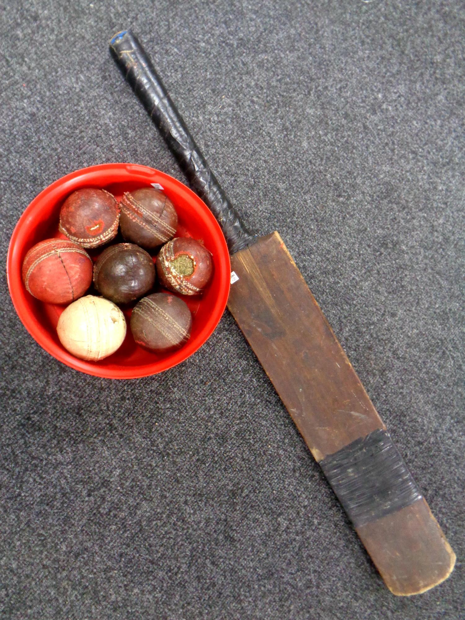 A vintage wooden cricket bat together with a box containing seven vintage cricket balls
