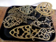 A tray containing seven antique brass trivets