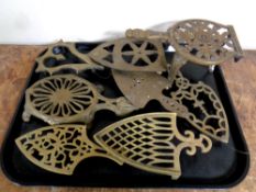 A tray containing seven antique brass trivets