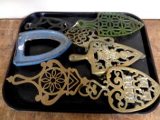 A tray containing seven assorted cast iron and brass antique trivets