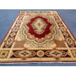 A machine made woolen rug with central medallion on red ground,