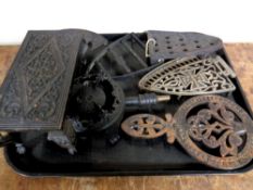 A tray containing seven antique cast iron trivets