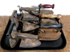 A tray containing eight antique cast iron flat irons