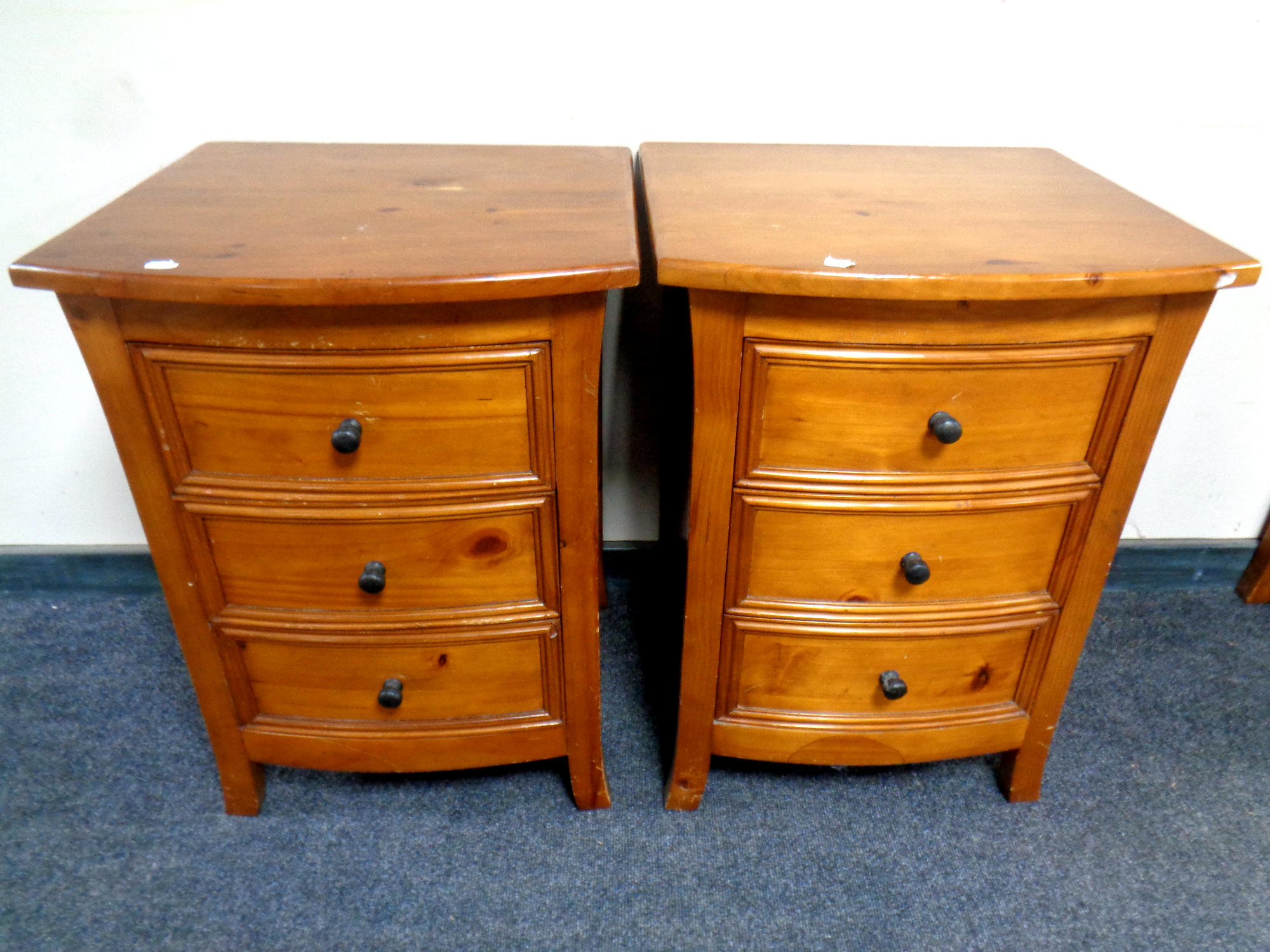 A pair of contemporary pine three drawer bow fronted bedside chests