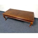 A contemporary coffee table on cabriole legs in a mahogany finish