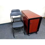 A drop leaf storage kitchen table containing six folding chairs