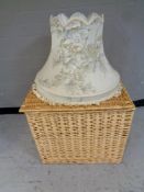 A large wicker hamper together with a standard lamp shade