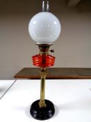 A Victorian brass Corinthian column oil lamp with red glass reservoir,