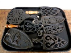 A tray containing seven antique cast iron trivets